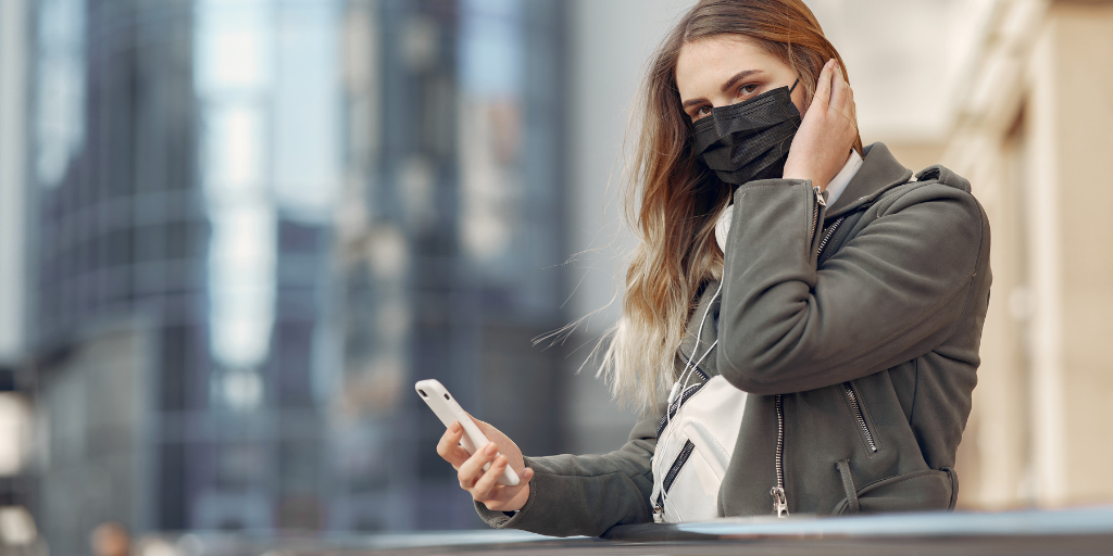 Woman with face mask holding mobile phone