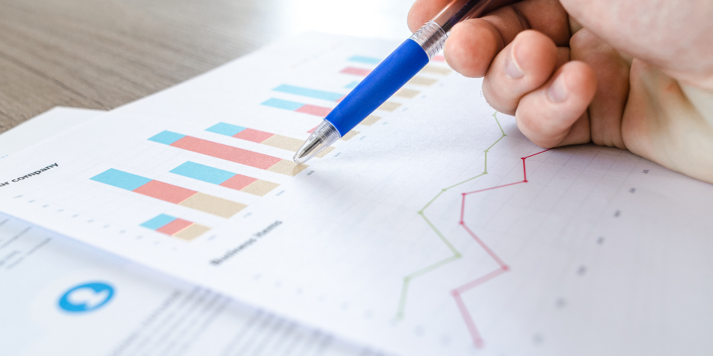 Pen on paper next to a bar chart and line graph