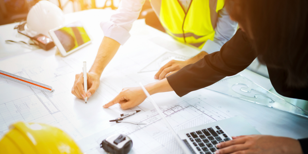 Two people at a construction site pointing to a table